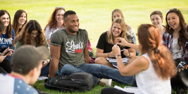 Students sitting together in the grass on campus.