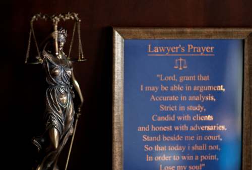 Bronze statue of a woman holding scales of justice next to a plaque that reads: Lawyer's Prayer. "Lord grant that I may be able in argument, Accurate in analysis, Strict in study, Candid with clients, and honest with adversaries. Stand beside me in court, So that today i shall not, In order to win a point, Lose my soul"