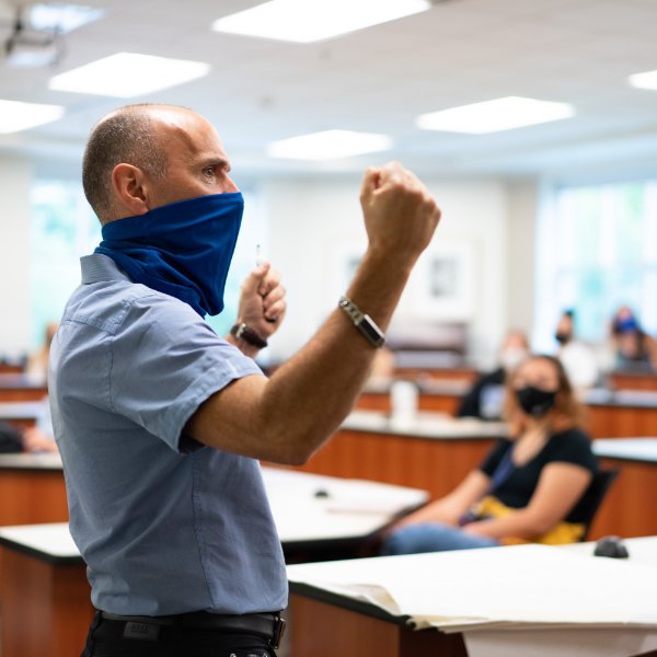 With a face covering, Kurt Ellenberger, professor of music, Meijer Honors College, stands in front of students in the Niemeyer Learning and Living Center.