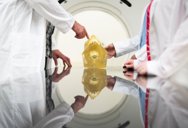  Hands are reflected while people wearing white lab coats point to an object. 