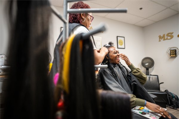 Amaris Beal laughs while a stylist works on her hair in a salon.