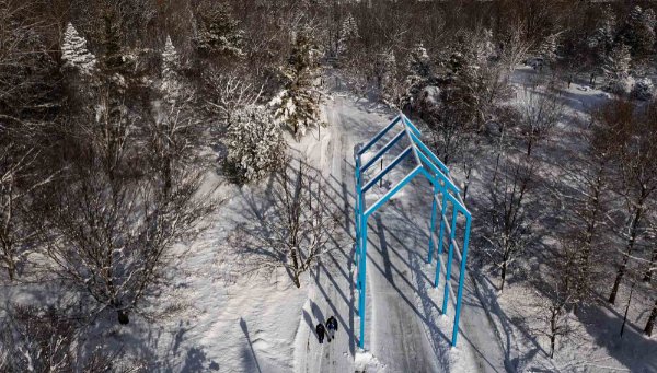  A blue art sculpture is seen on a snow-covered college campus from a drone.