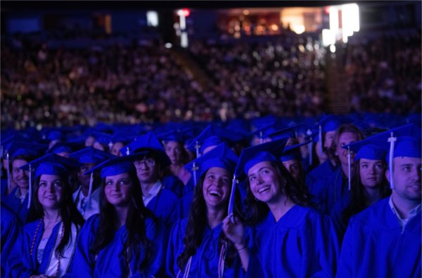 Graduates smile as they watch a video playing on the big screen at Commencement.