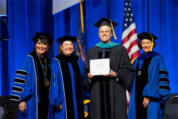 GVSU officials pose and smile with guest speaker Timothy Shriver, who received an honorary degree. 