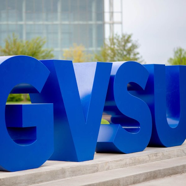 Large blue letters on a small cement pedestal spell out GVSU.