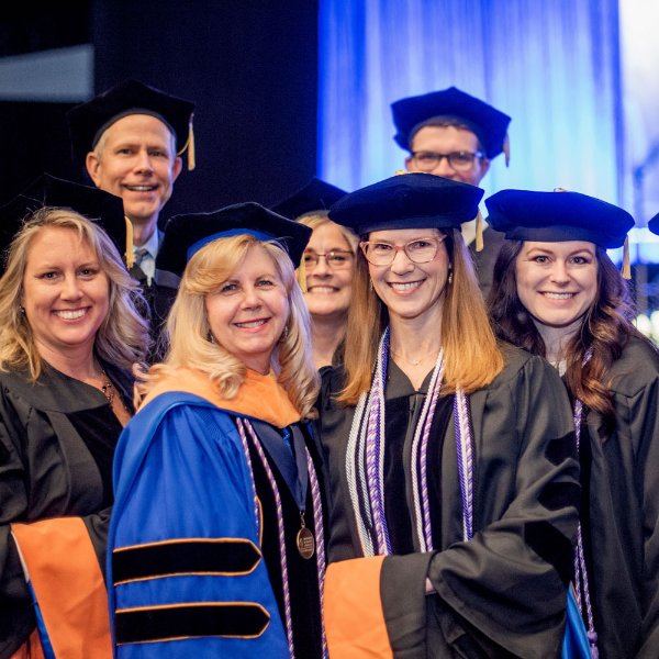 two rows of faculty and students in academic regalia at a commencement ceremony
