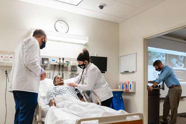 Students majoring in physician assistant studies practice their clinical skills in the Simulation Lab in in the Cook-DeVos Center for Health Sciences. Andrew Booth, associate professor of physician assistant studies, is at far right.