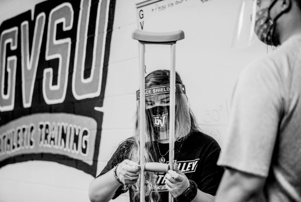 Wearing a face shield, Maylee Bowers does a crutch fitting during her principles of athletic training lab on the first day of classes.