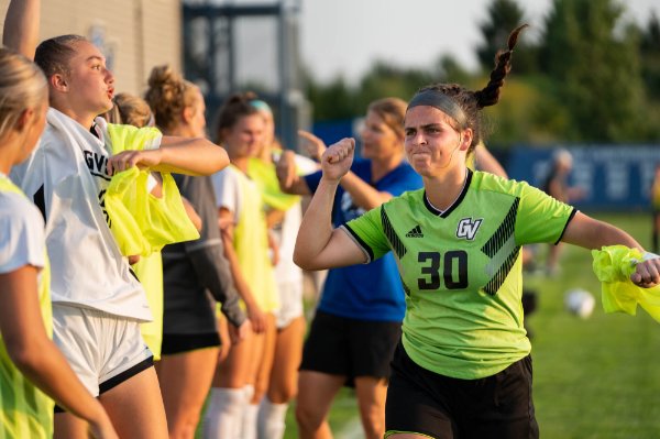 A soccer player pumps a fist to teammates along the sidelines during a game. 