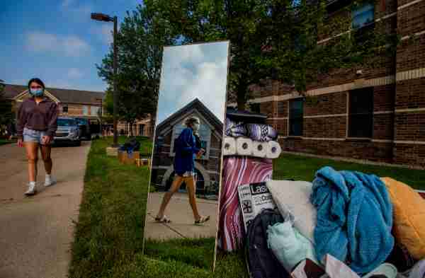 Student is photographed through the reflection of a mirror that is sitting in a pile of a student's belongings.