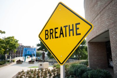 A yellow sign with the word "breathe" is seen outside a building.