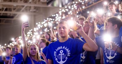 student hold cell phone lights in the bleachers