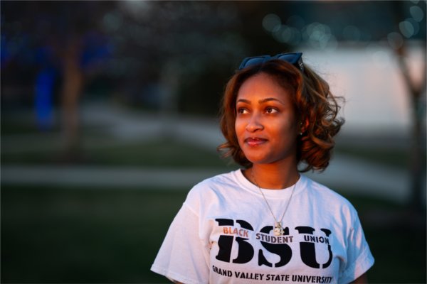 Maya Woodson stands outside on Grand Valley's campus in a "Black Student Union" Shirt.