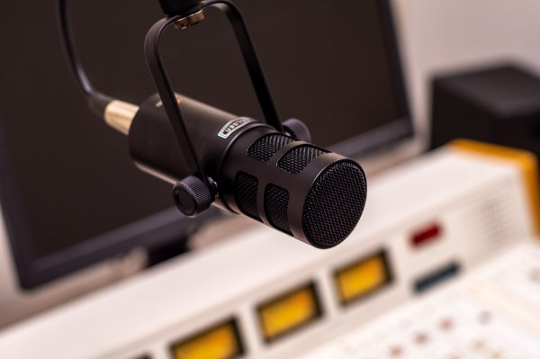 A studio microphone for a radio station hangs over a control board.