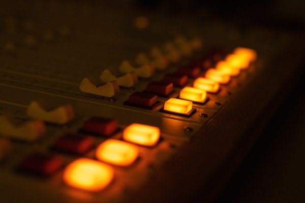 The buttons on a radio station control board are lit up in the darkness.