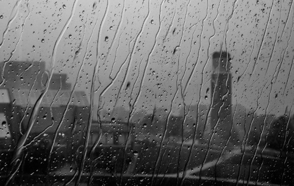  Rain drops roll down a window in focus in the foreground, while buildings on the GVSU campus are identifiable in the background.