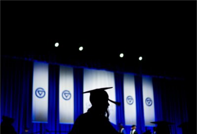 A graduate is silhouetted against blue and white banners.
