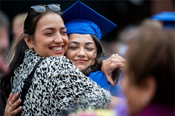 A graduate hugs their family member. 