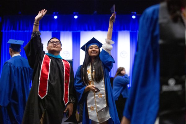  Two graduates wave to the audience. 