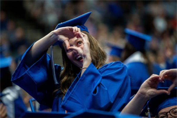  Graduates make heart gestures with their hands. 
