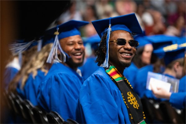  A graduate wearing sunglasses smiles.