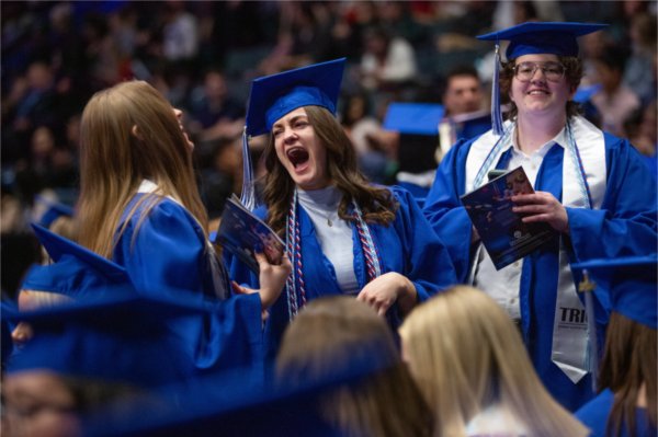  Graduates laugh together during Commencement. 