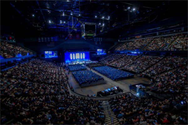 An overall photo showing a full arena of guests during a university commencement.  
