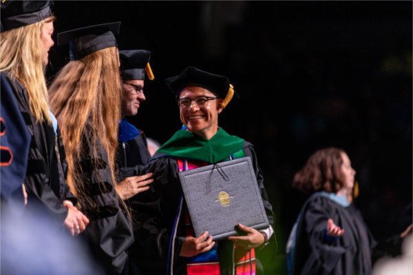  A person smiles as they receive their diploma.