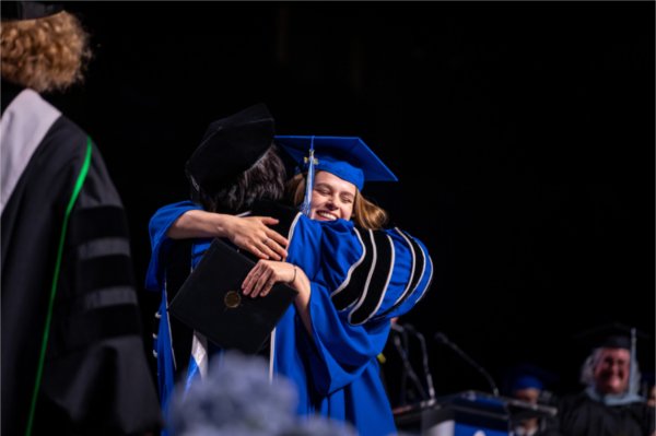  A graduate hugs the university president when receiving their diploma.