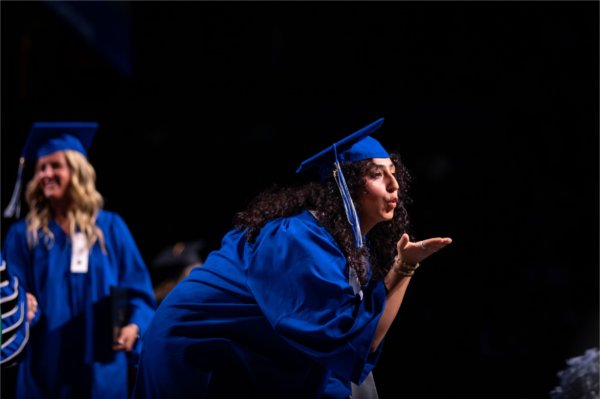 A graduate blows a kiss to the crowd. 