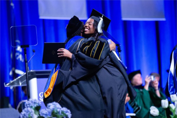  A graduate hugs a dean as they receive their diploma. 