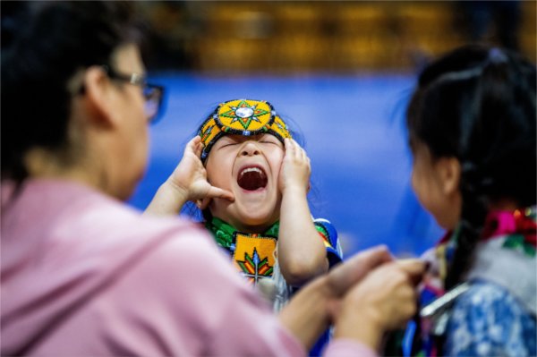  A child wearing colorful regalia laughs. 