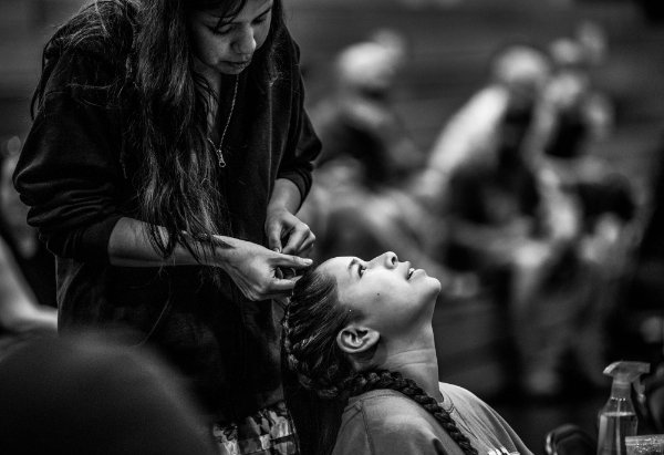Gladys Martin, left, braids the hair of her friend, Waaba Medawis, right, before the start of the Pow wow.