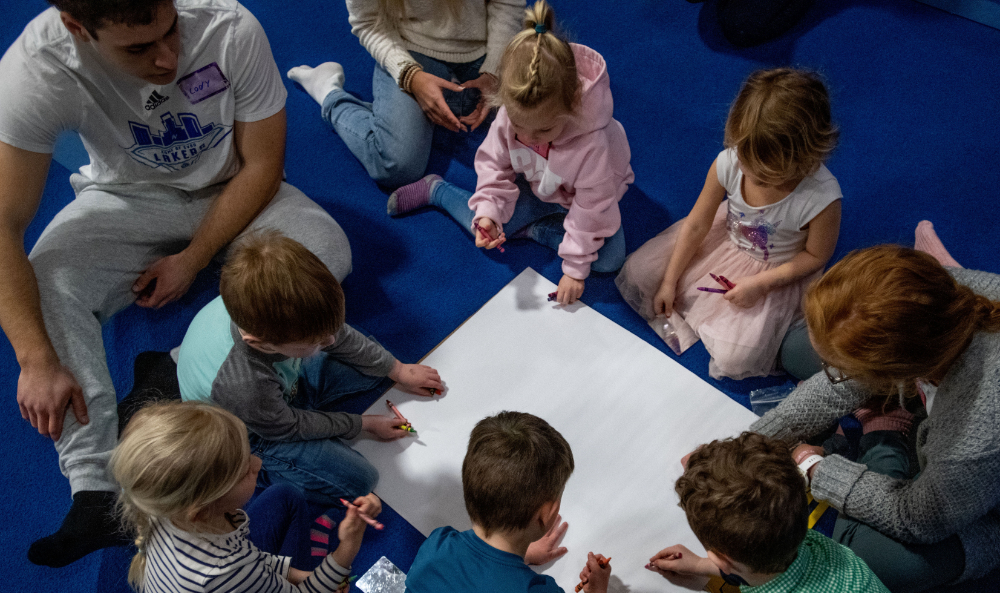 Young children writing on a paper in class.