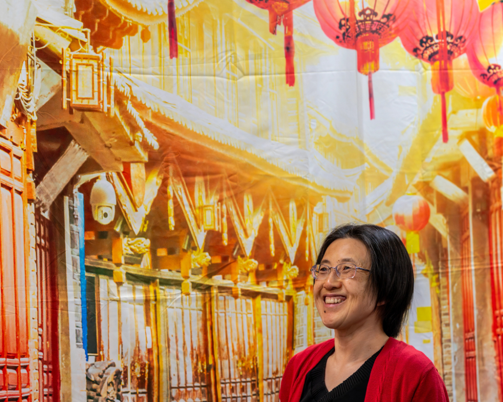 East Asian Studies professor talks in front of Chinese backdrop.