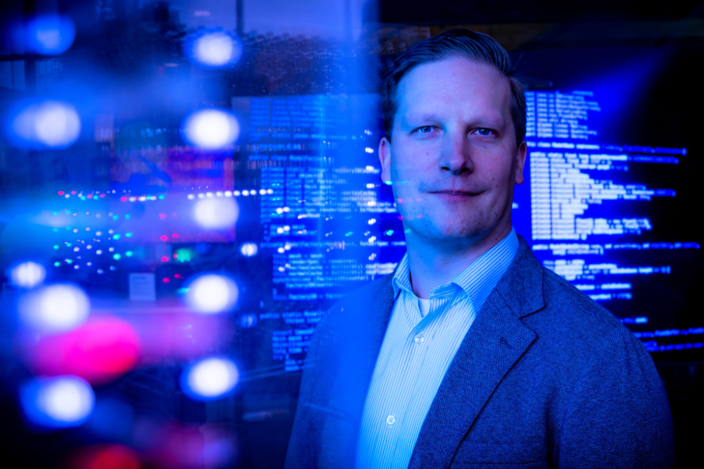 A computer professor with a screen around him.