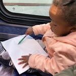 young girl coloring on bus