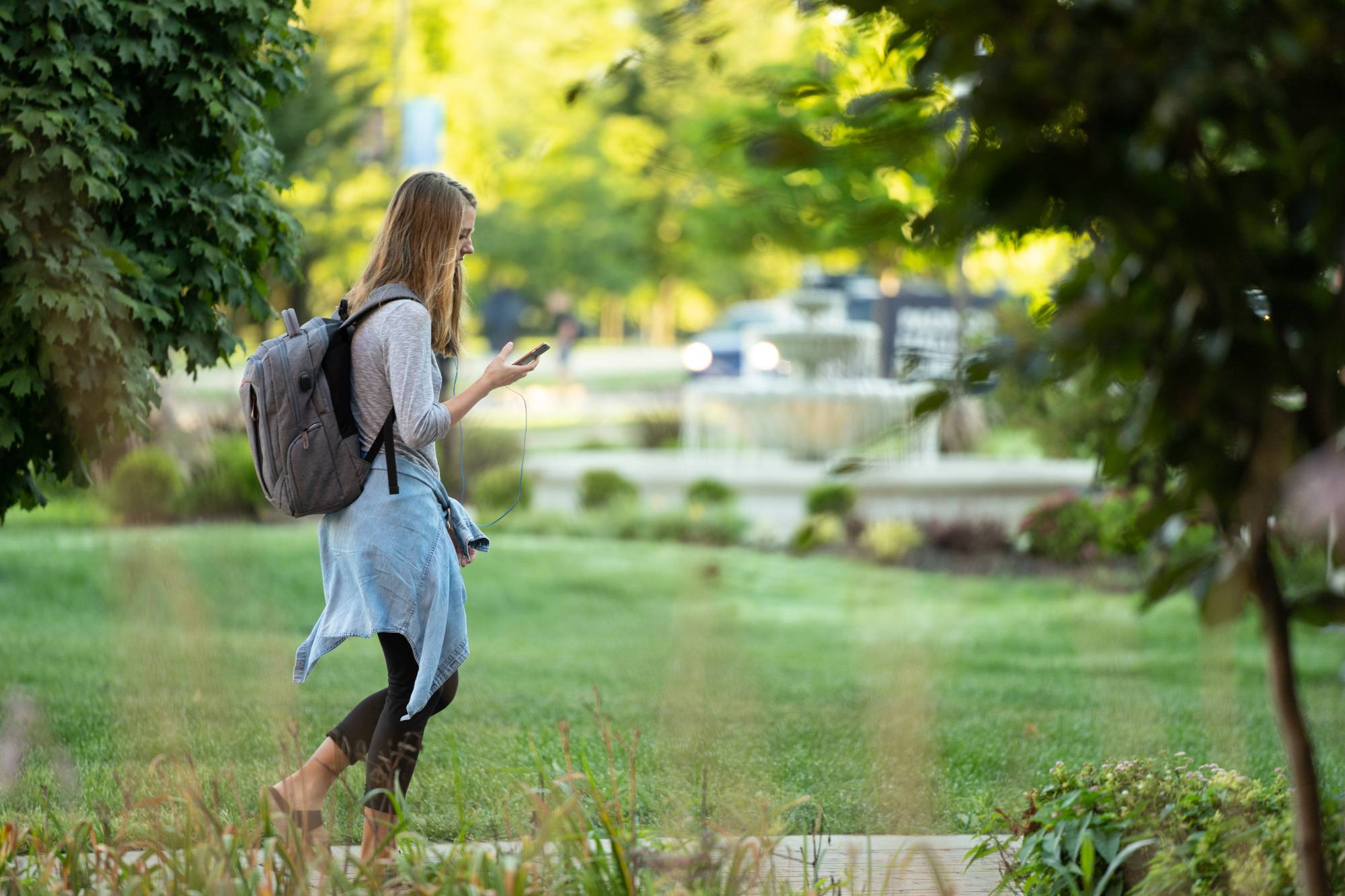 Student walking outside wearing white headphones