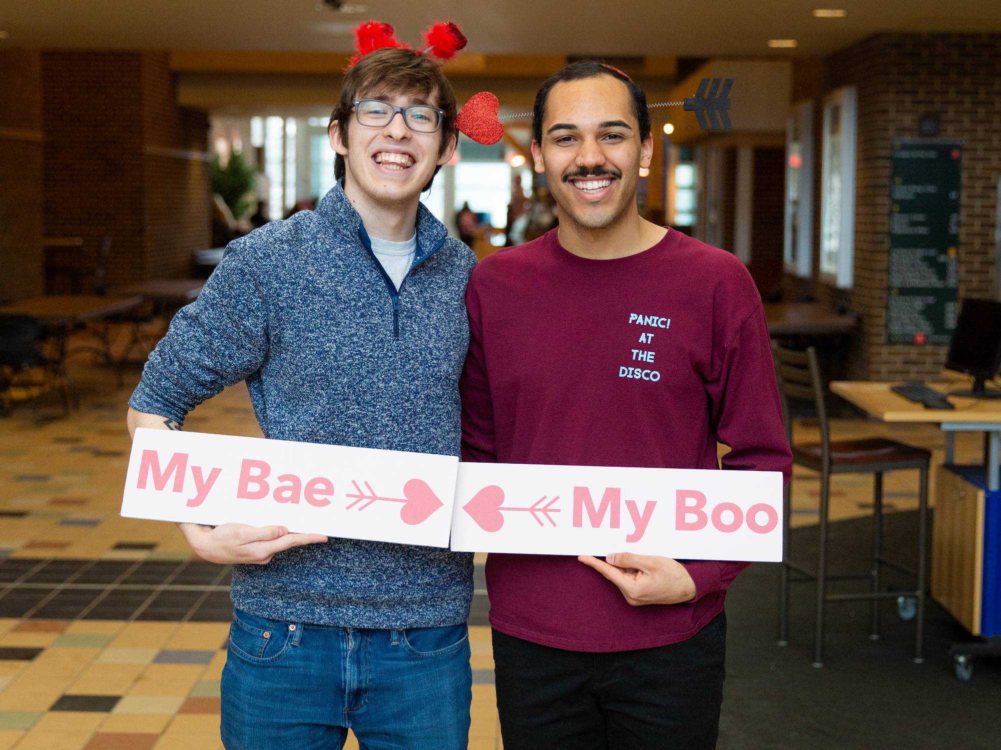 GVSU couple holding signs labeled  "my bae and my boo"