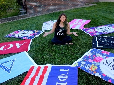 Jordan Sheatzley sits surrounded by Greek Life flags