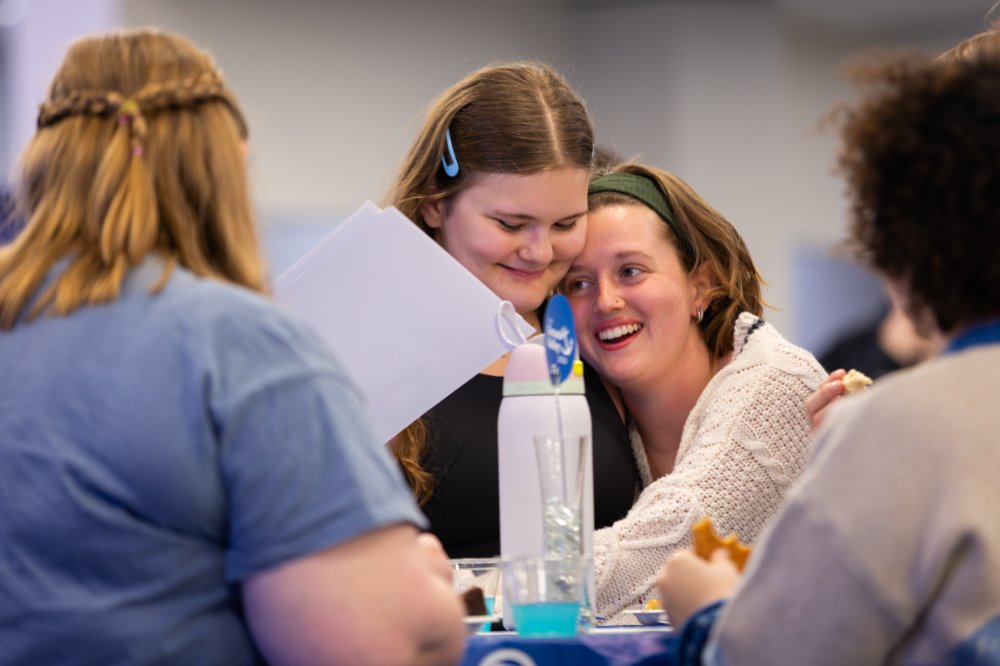 Two students hugging at an event inside Kirkhof