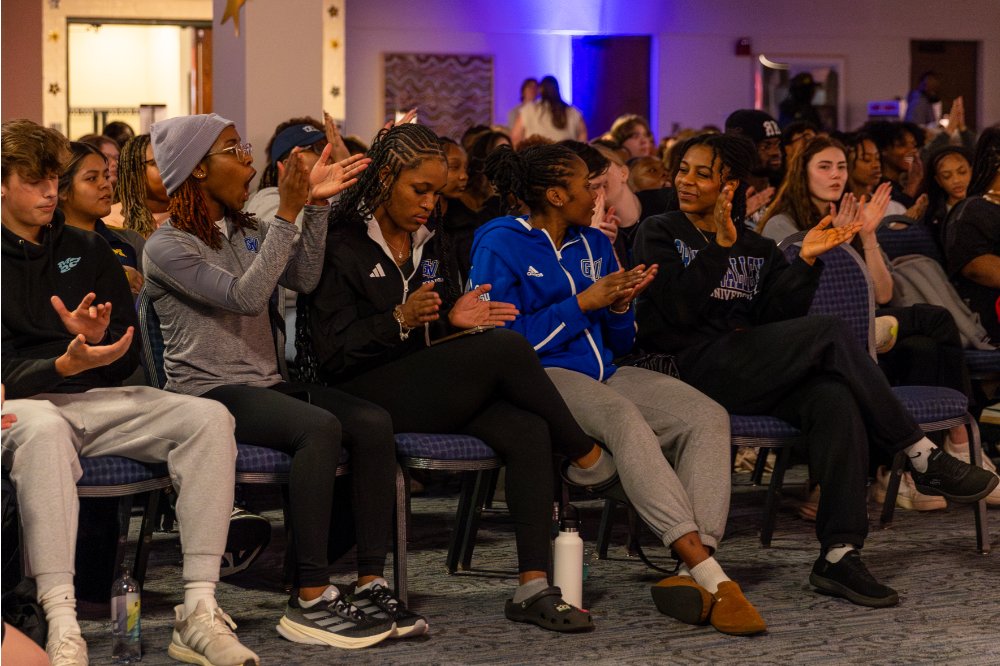 Students sitting in chairs while clapping and applauding
