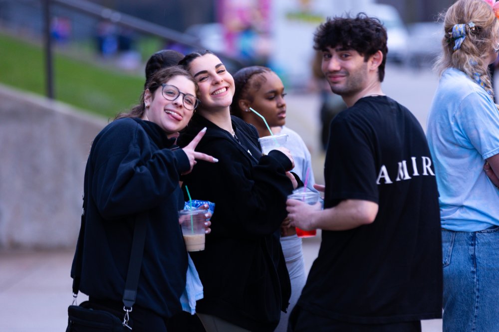 three students standing and smiling at the camera