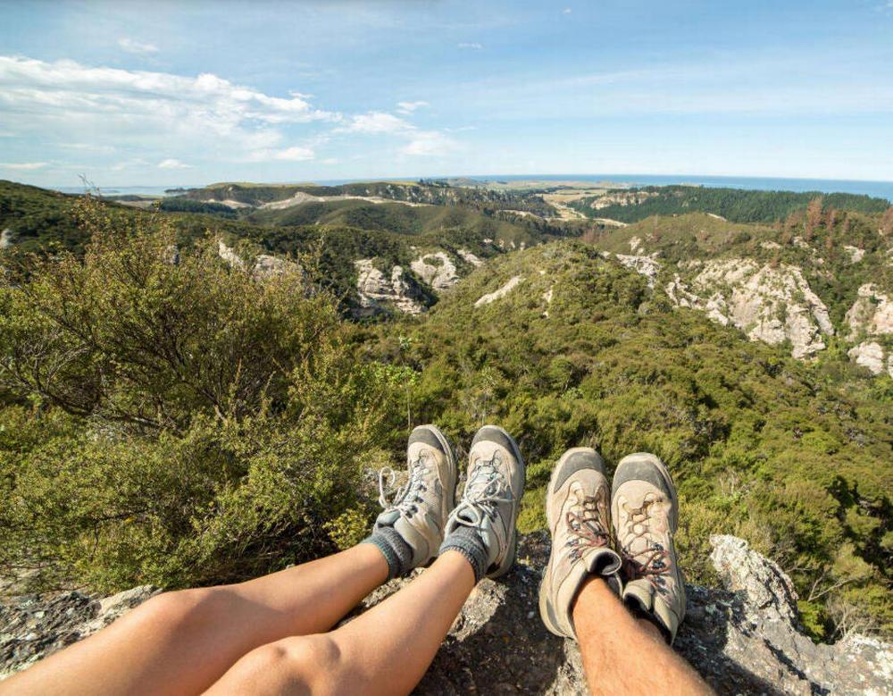 2 hikers legs and feet in the foreground of a scenic mountain vista
