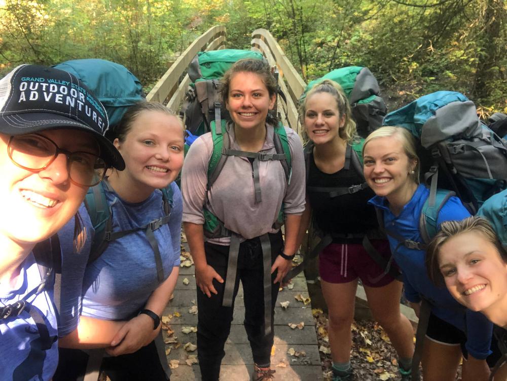 5 backpackers posing for a picture in front of a wooden bridge at the Manistee River Trail