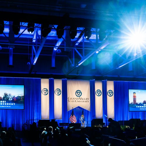 GVSU Commencement stage with blue lights and banners hanging with the GVSU logo