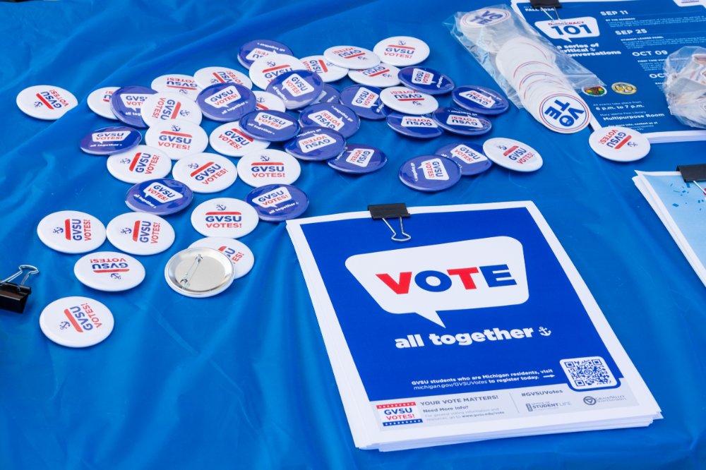 GVSU Votes! buttons, posters, and stickers displayed on a table