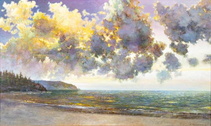 Sunlit clouds over a beach and body of water.