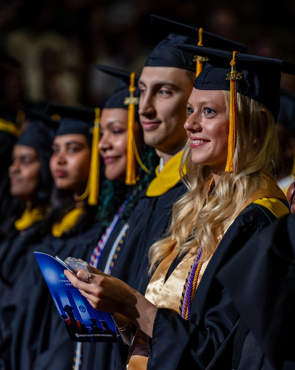 master's graduates smile during Commencement wearing their black cap and gown