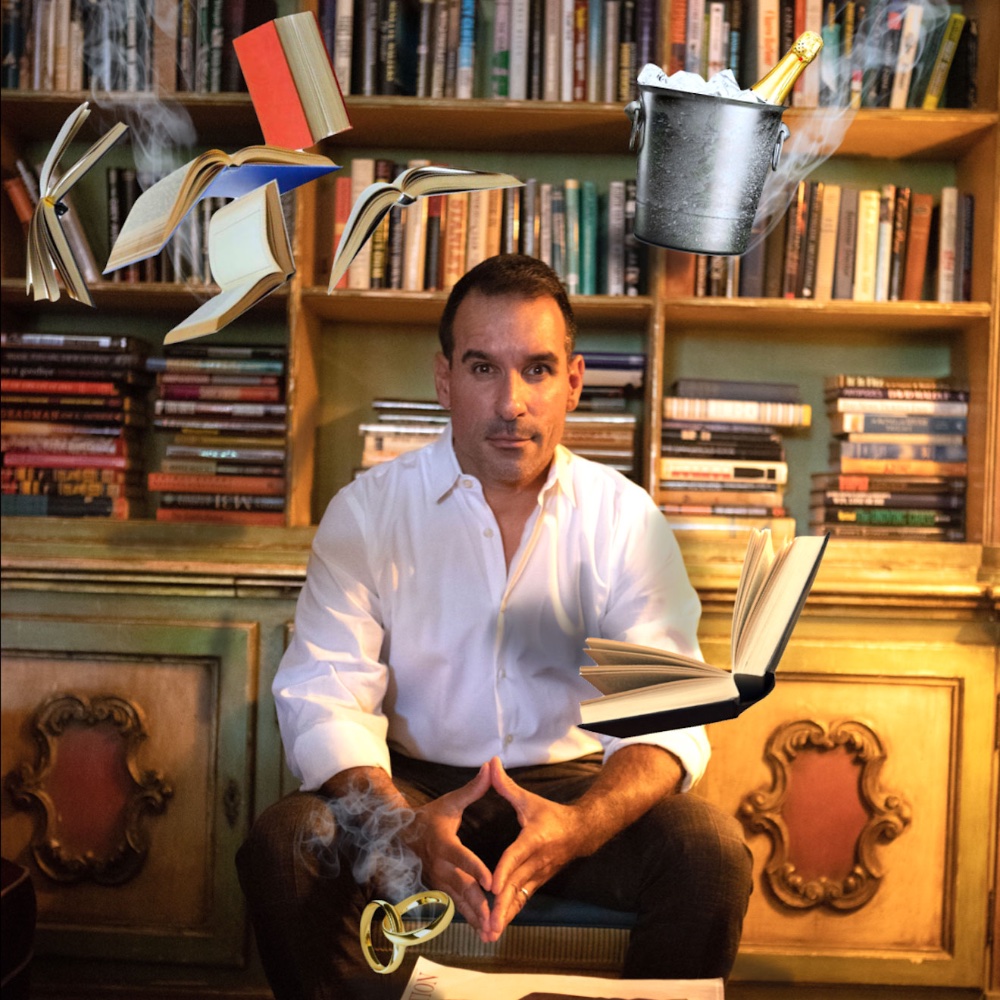 Man sitting in front of a bookshelf with floating books, rings, and a bucket all surrounding him